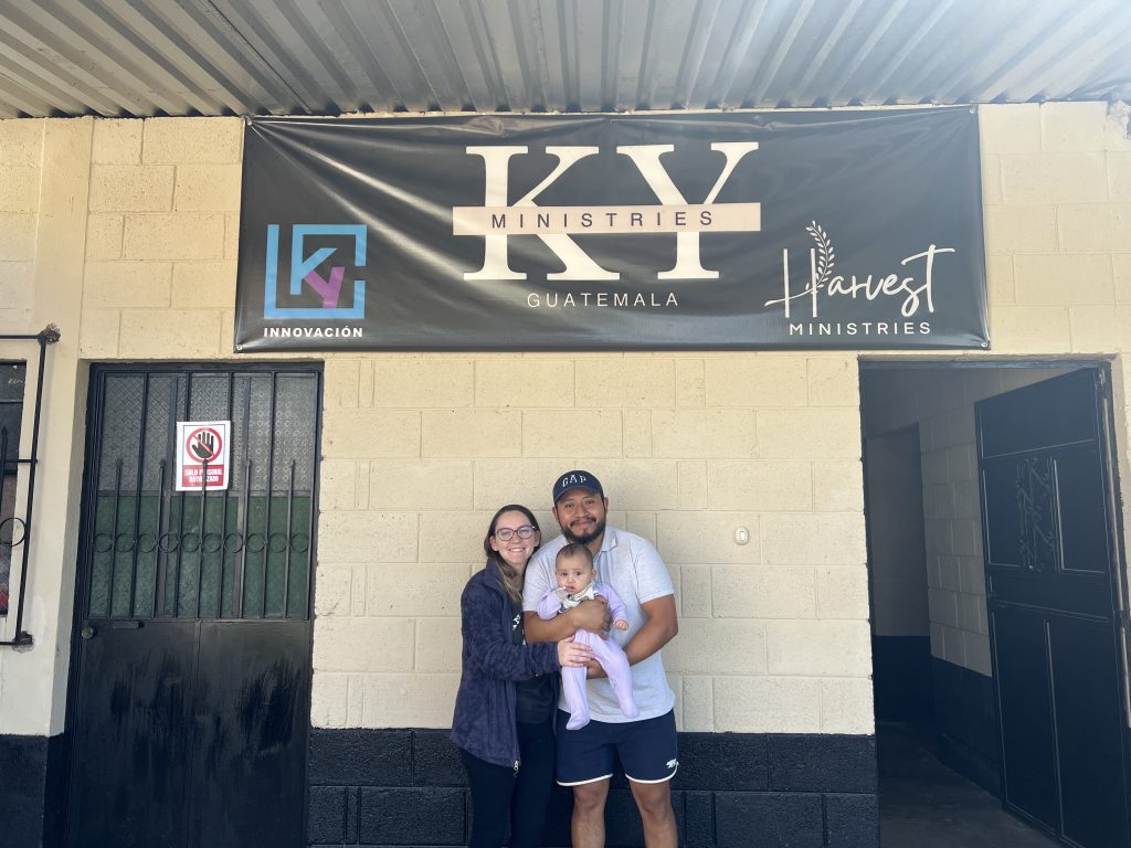 Husband and wife hold child under KY Ministries sign 