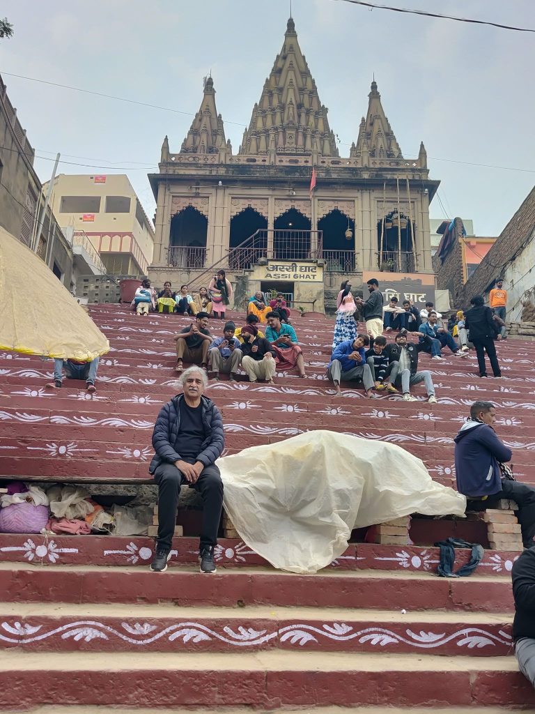 Man sits on steps of building in Varanasi (city on Ganges river in Northern India)