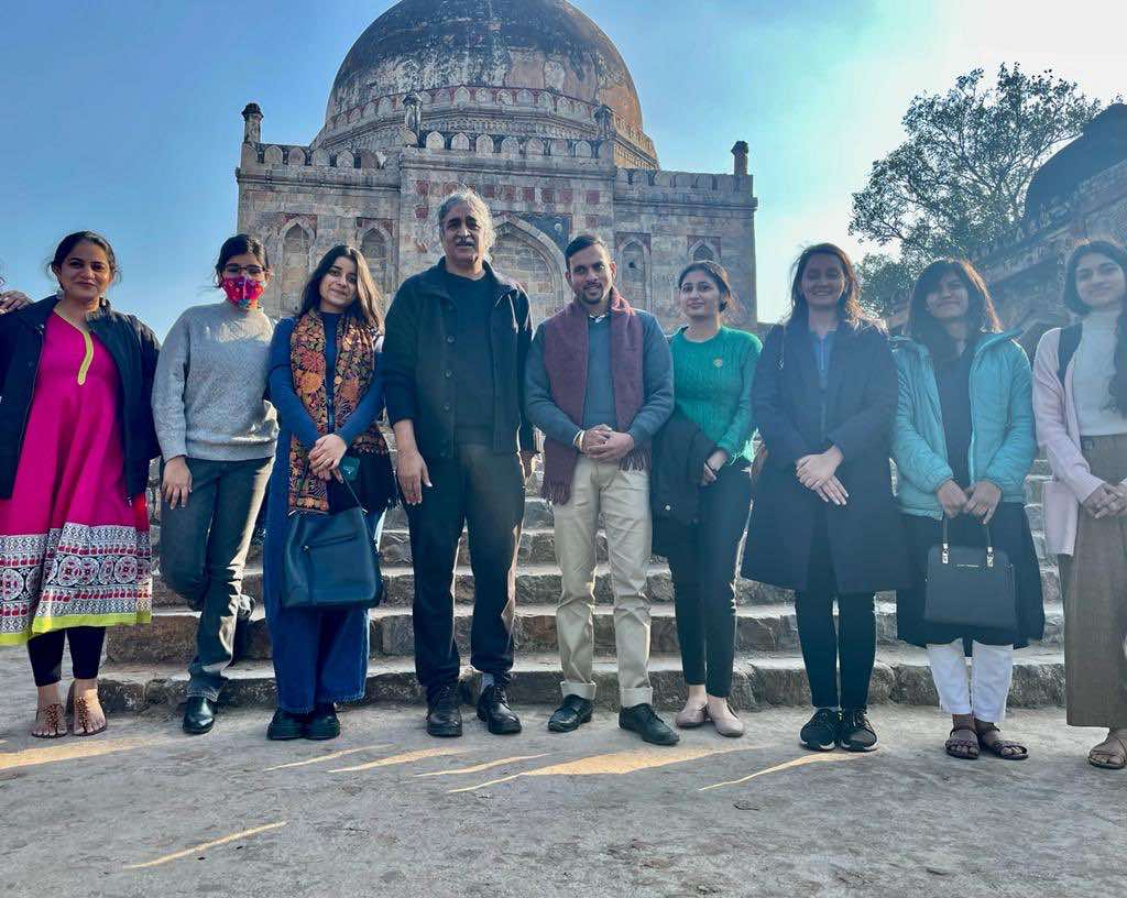 Nine people stand in front of medieval building in India