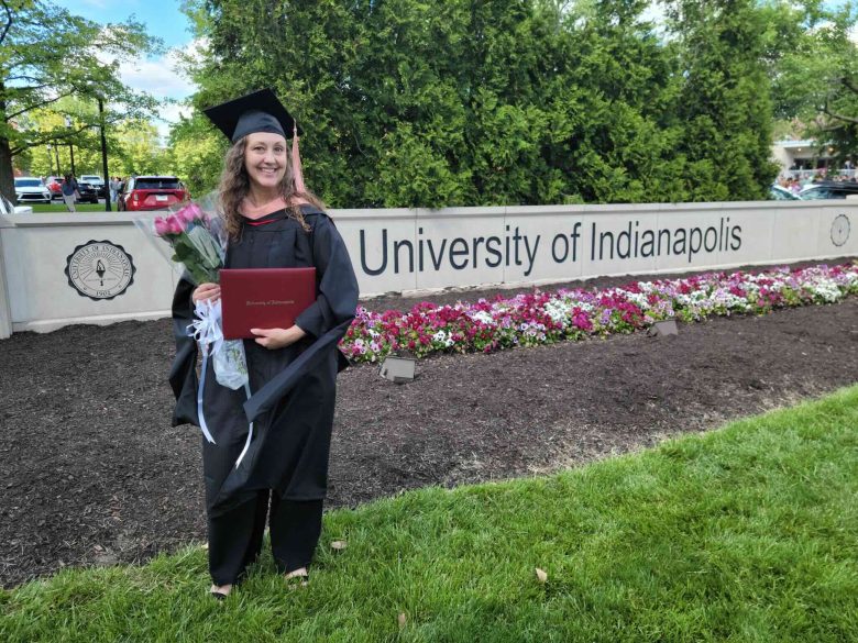 Casey Long poses with her diploma in front of the University of Indianapolis sign
